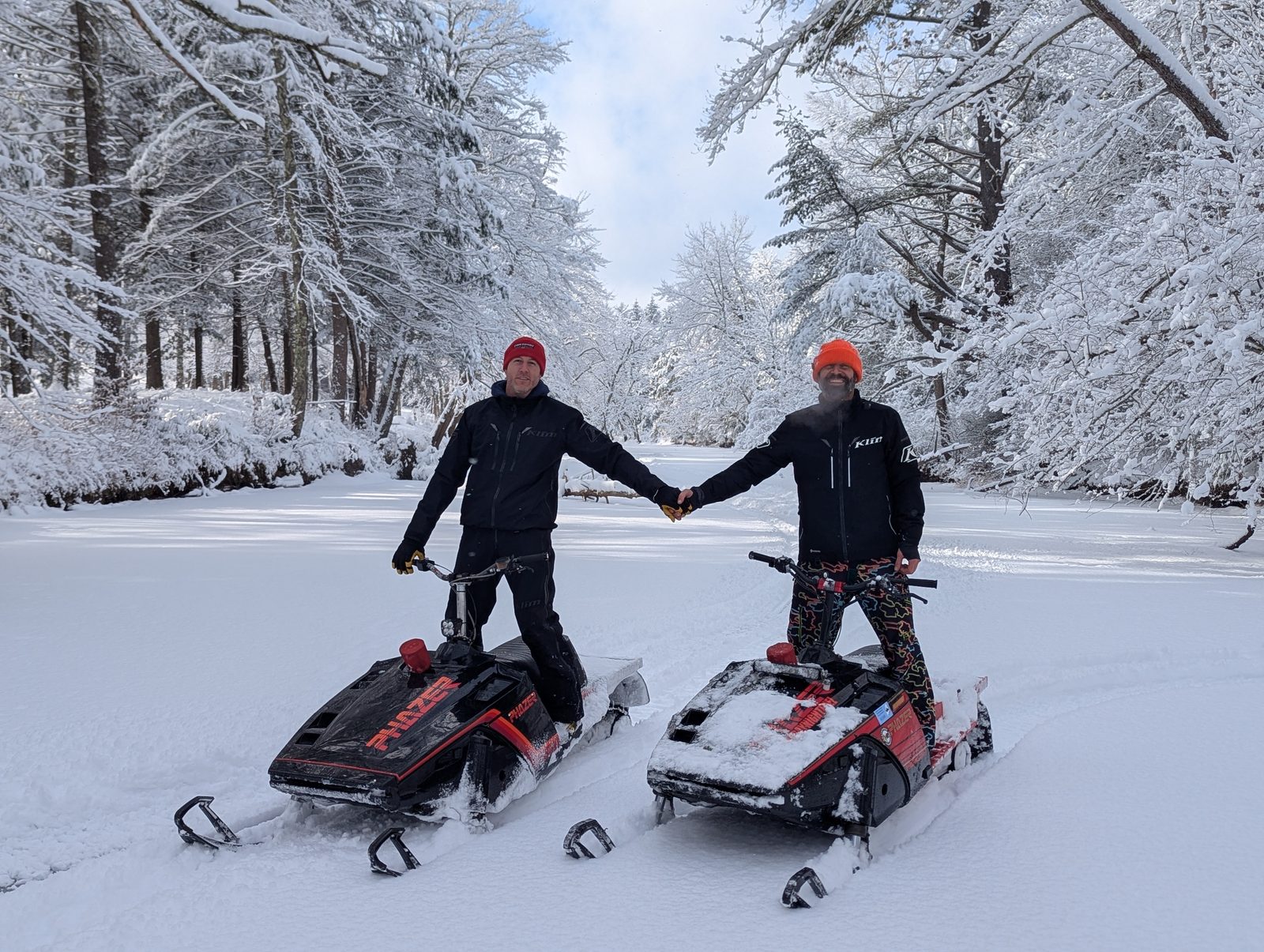 Two riders on vintage Yamaha Phazers on a snow-covered river